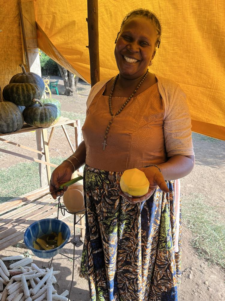 A Ugandan market vendor smiling with fresh mango
